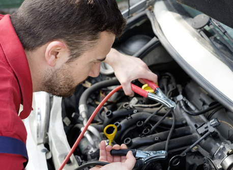 mechanic working on car engine with electricity cables