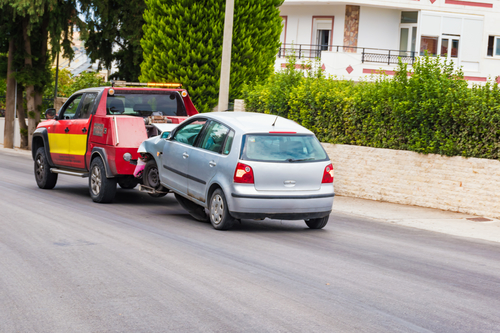 Crashed car being towed away by tow truck after accident