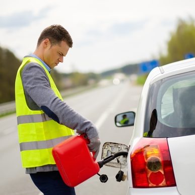 Man refuelling her car on a highway roadside